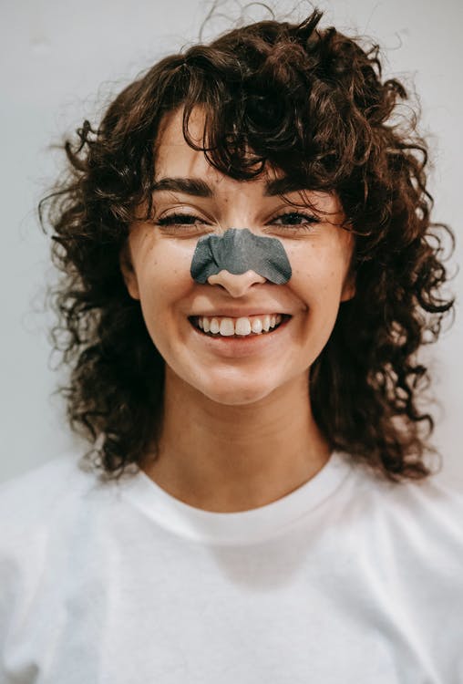 Glad kvinde efter næseoperation med plaster på næsen